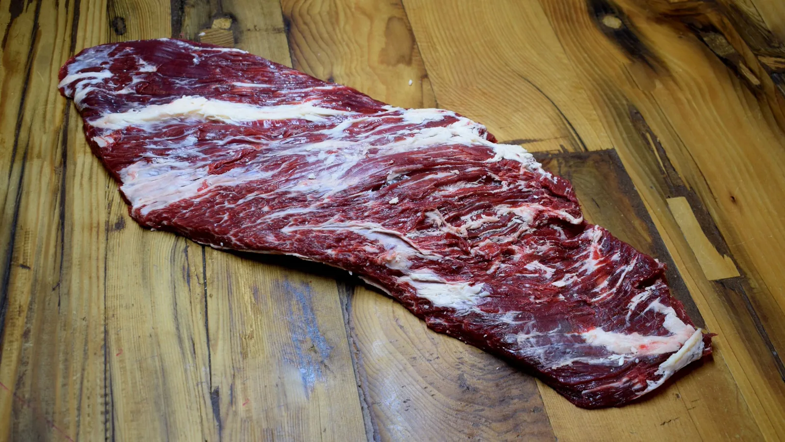Uncooked skirt steak laid out on a wooden board