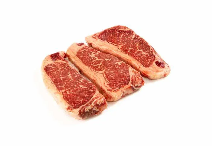 Three uncooked entrecôte portions against a white background