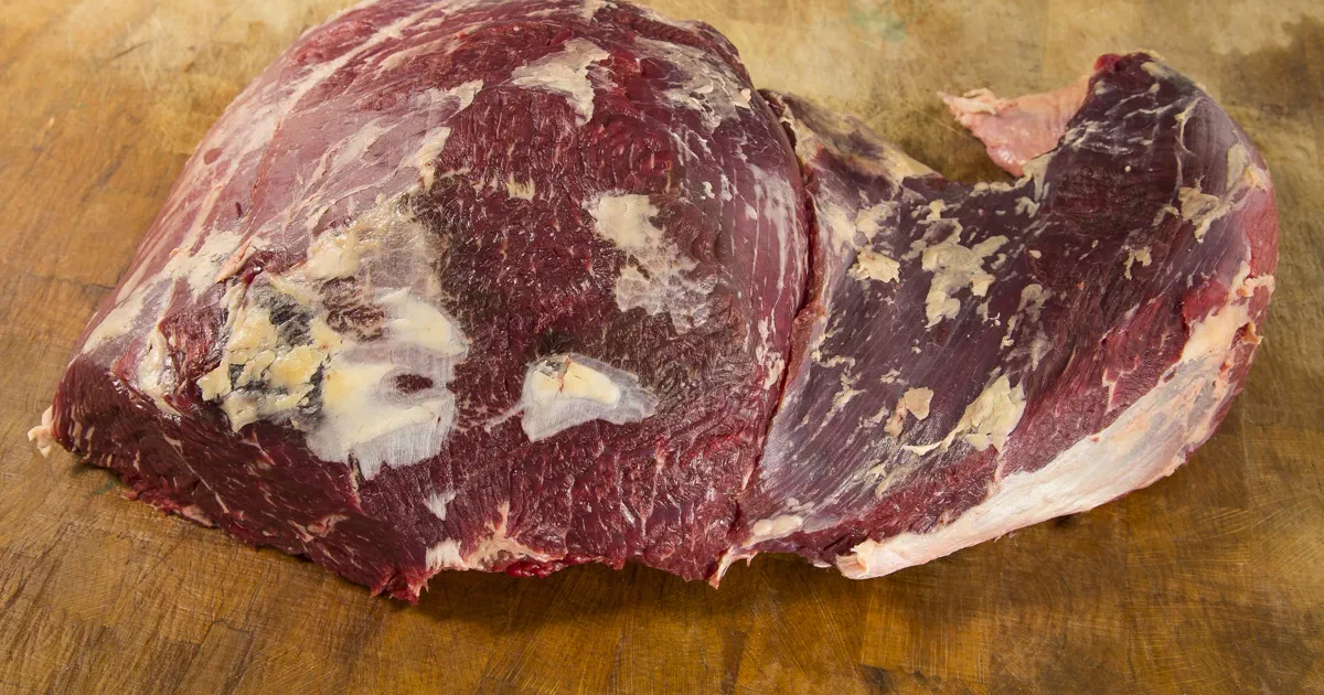 Pieza de vacuno con grasa visible sobre tabla para guía sobre carne de calidad