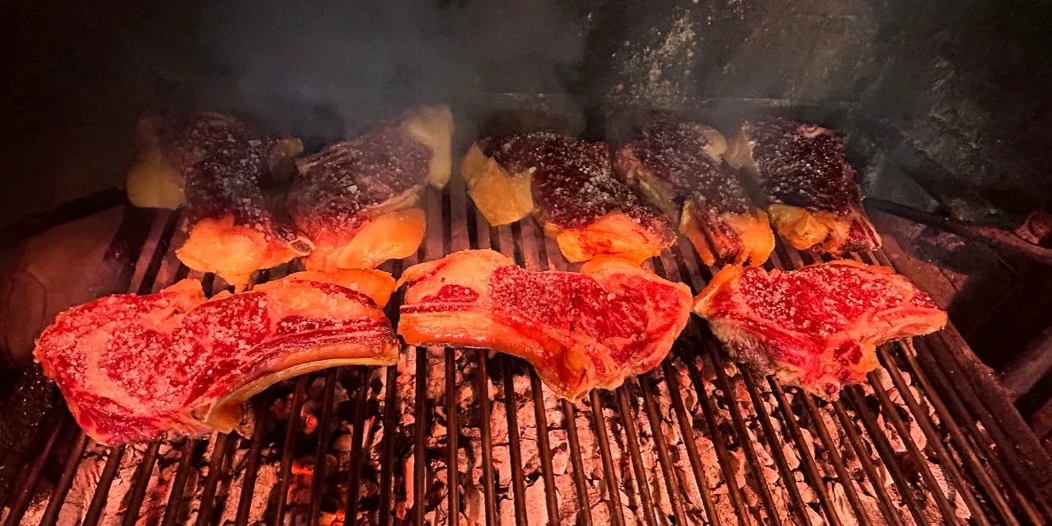 Chuletones sobre una parrilla encendida con brasas y humo